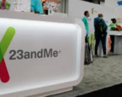 23andMe sign with people standing around a table in the background