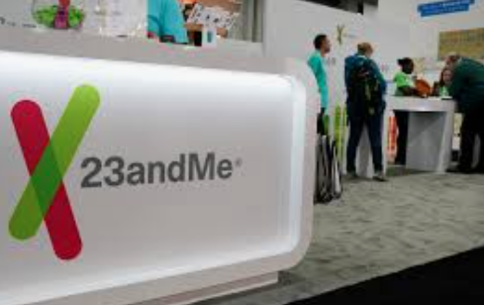 23andMe sign with people standing around a table in the background