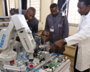 African robotics workers around machine