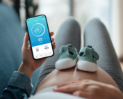 Pregnant belly with baby shoes and monitoring app