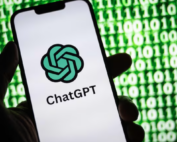 Hand holding phone with ChatGPT and code in background