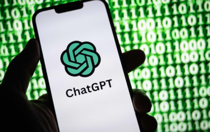 Hand holding phone with ChatGPT and code in background